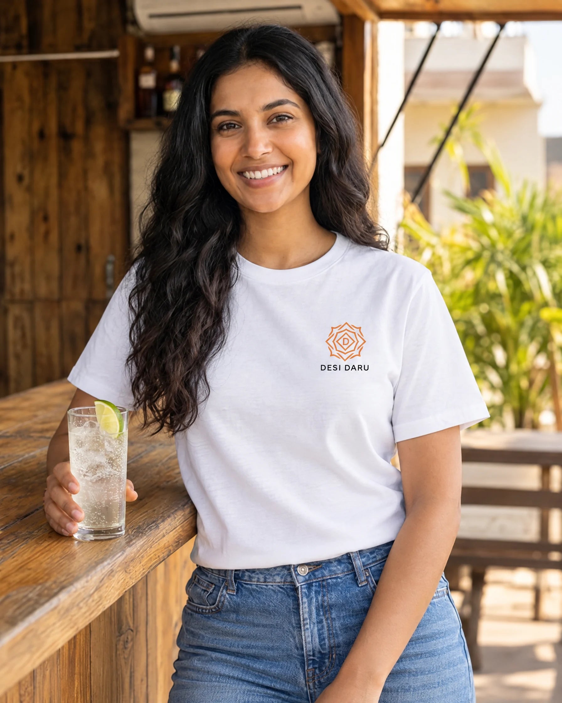 Woman wearing the Desi Mango Soda white tee with the Desi Daru logo at a rooftop bar